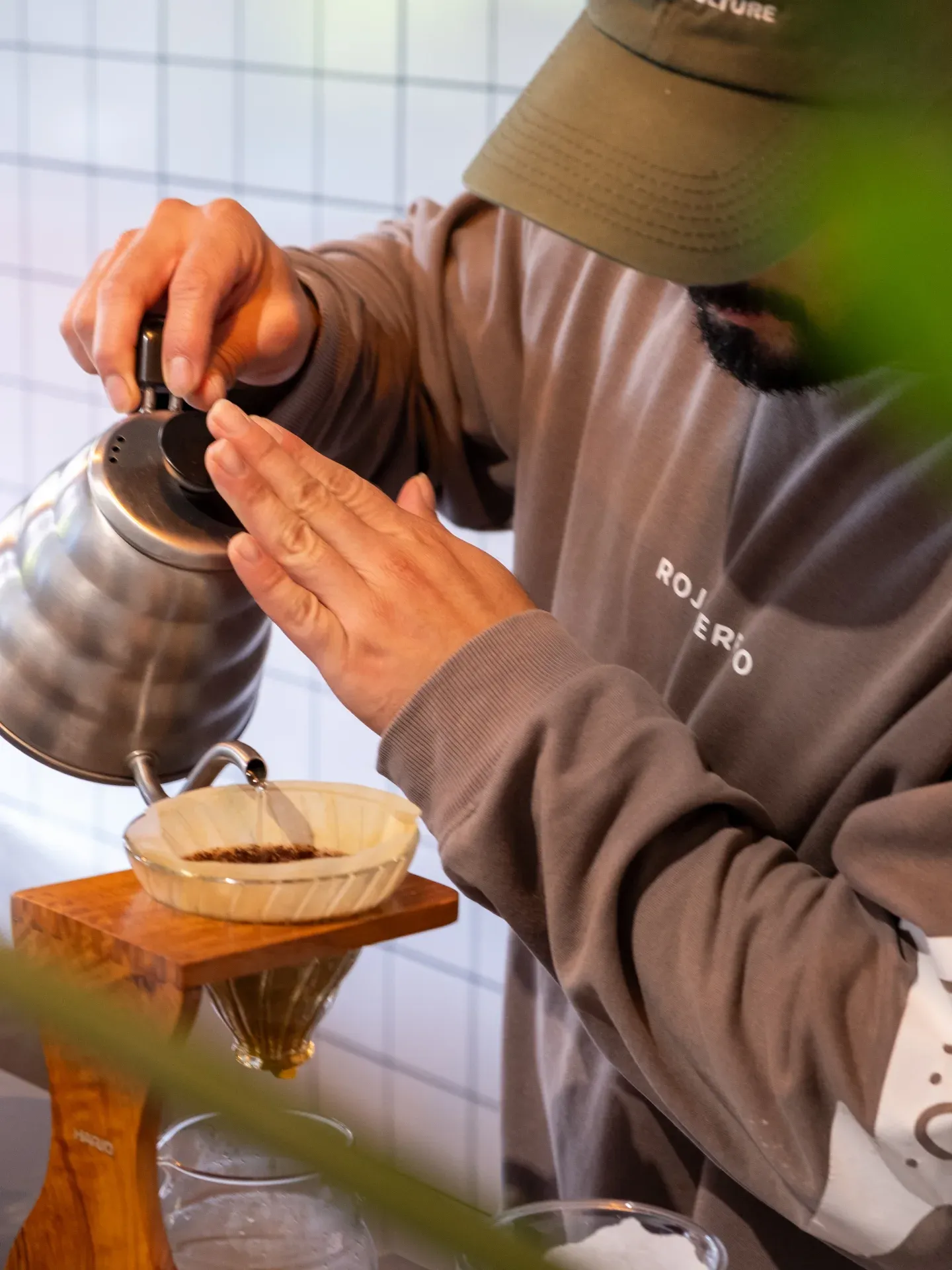 Barista vertiendo agua con una tetera de cuello de ganso sobre un filtro