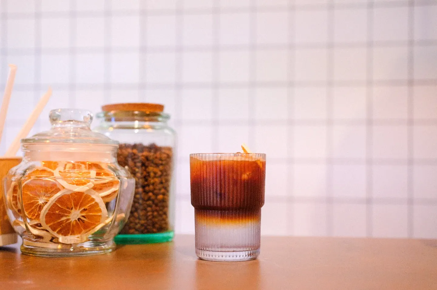 Coldbrew tonic con hielo junto a un frasco con rodajas de naranja deshidratada