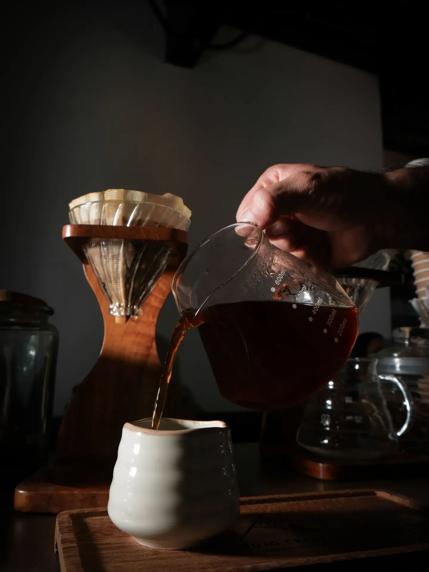 Café filtrado servido desde la jarra a una taza de cerámica blanca